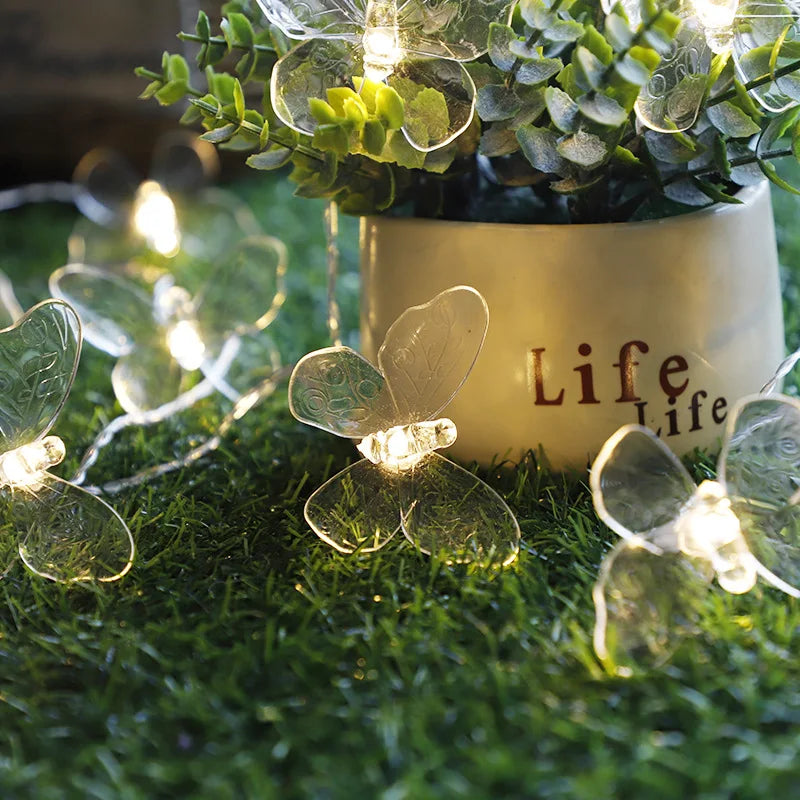 Mariposas transparentes encendidas junto a una maceta con planta