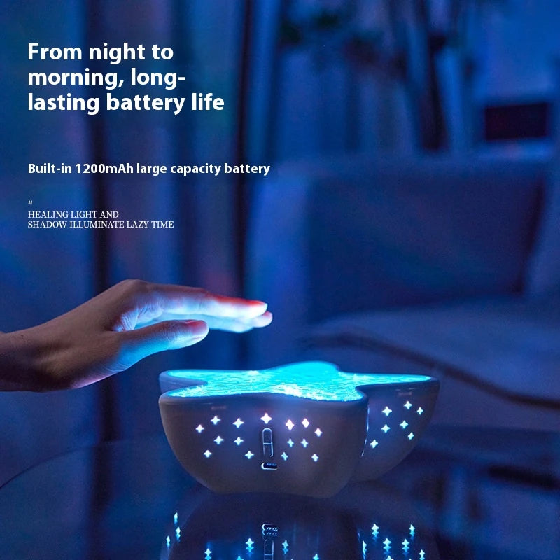 A hand over Starfish Lume glowing blue in a dark room